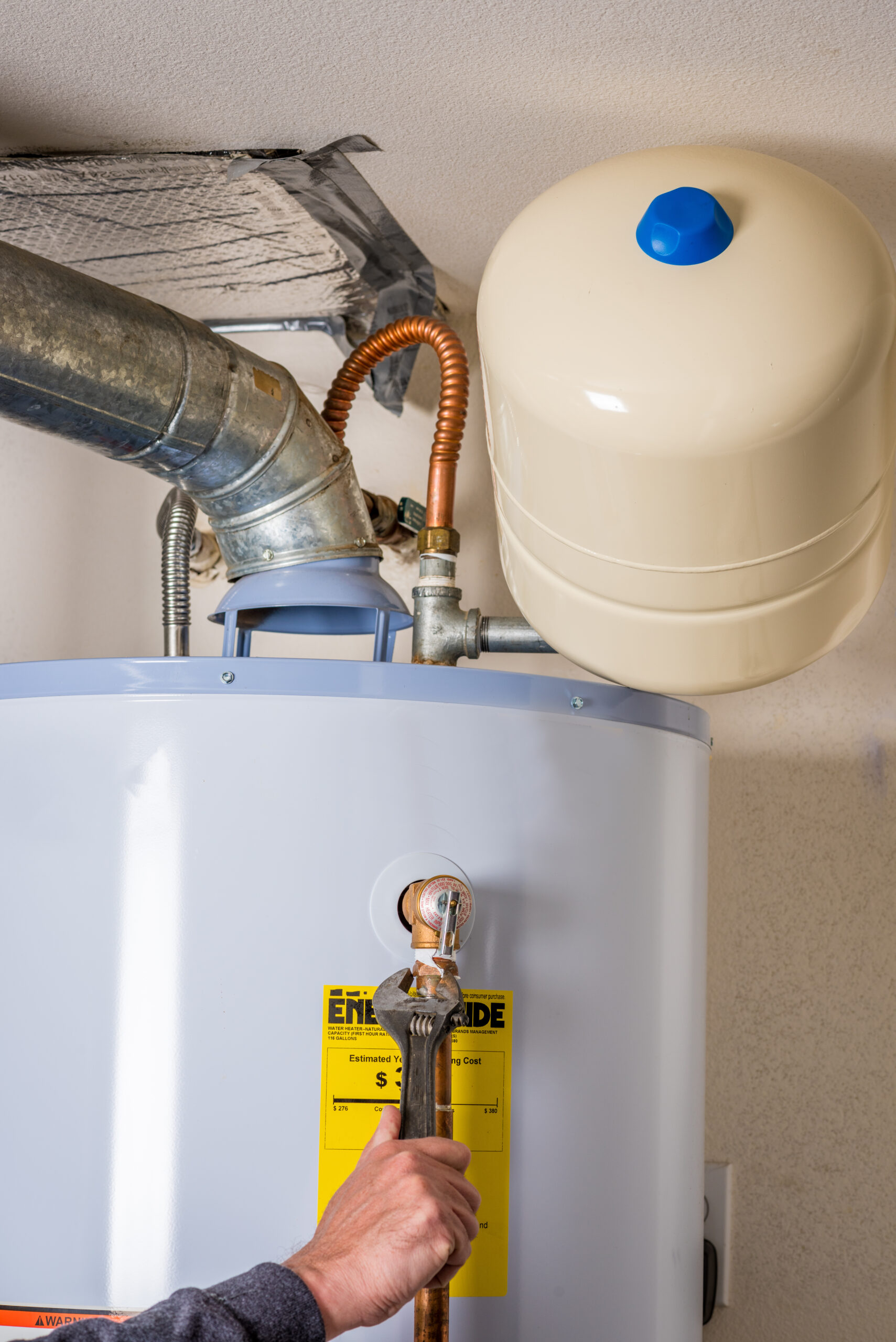 Plumber tightens a fitting on a hot water heater with a wrench